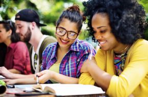 Two women looking a textbook outdoors